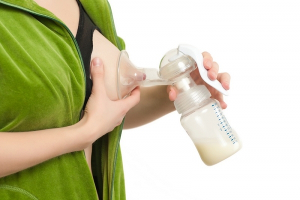 young woman pump out milk full full breast to bottle