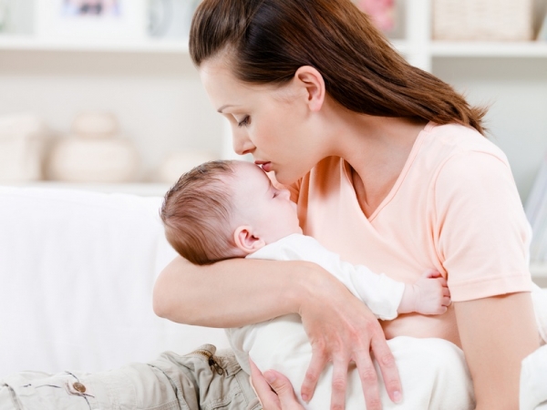 Mother kissing її sleeping baby