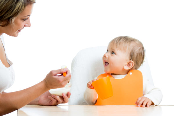 mother spoon feeding her baby girl